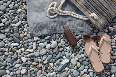 Photo of Stylish bag, flip flops and spray on stones outdoors, flat lay. Space for text