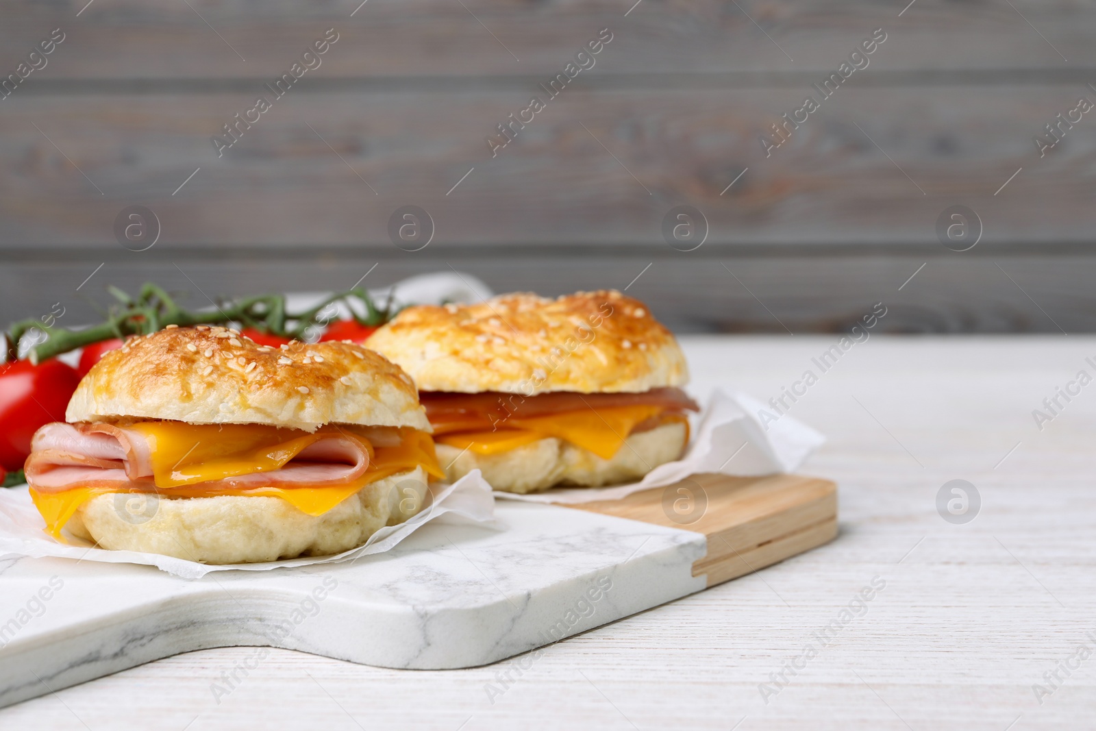 Delicious bagels with ham and cheese on white table. Space for text Photo of Delicious bagels with ham and cheese on white table. Space for text