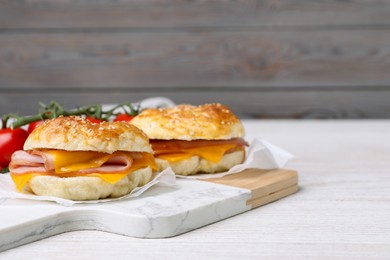 Photo of Delicious bagels with ham and cheese on white table. Space for text