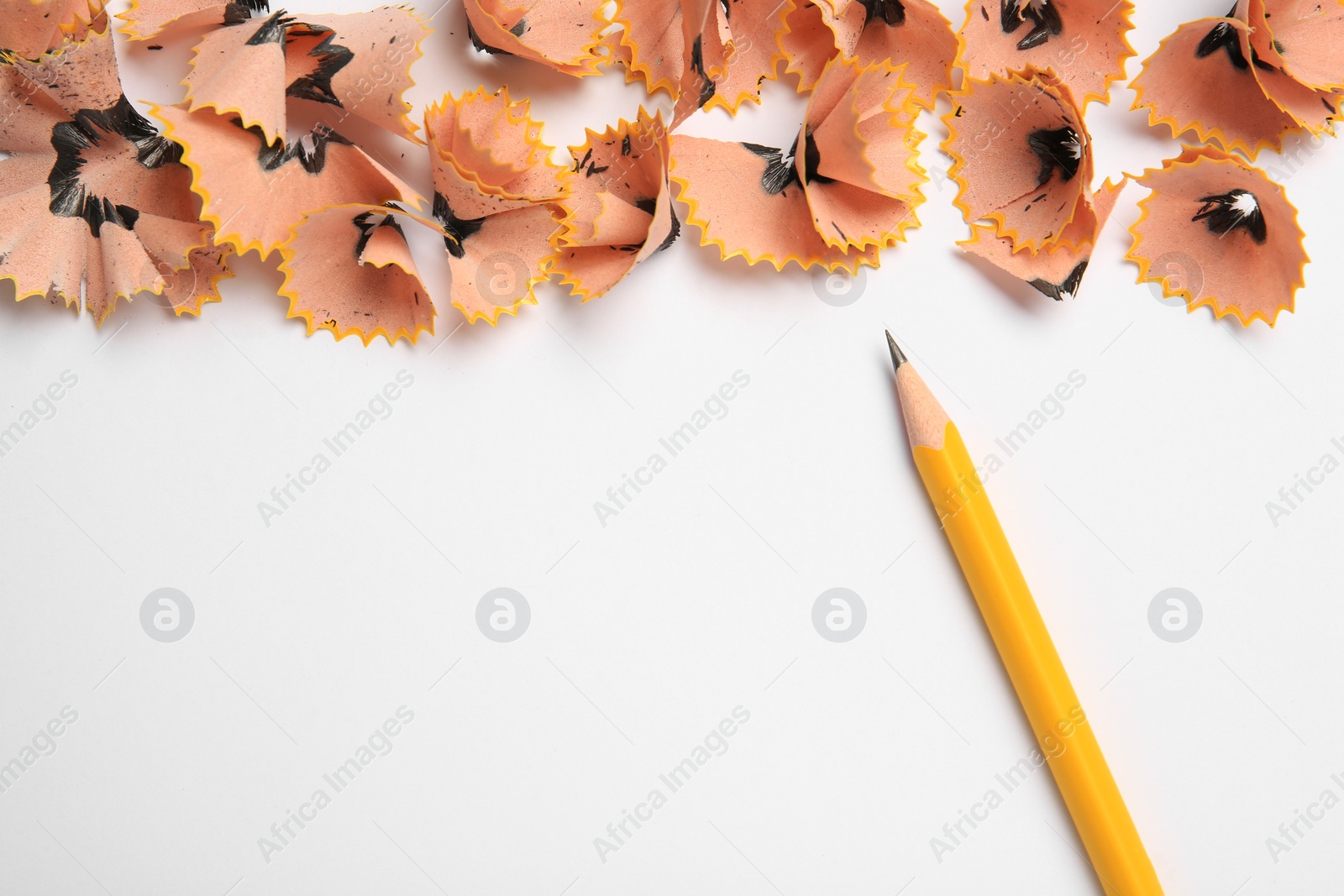 Photo of Sharp graphite pencil and shavings on white background, top view. Space for text