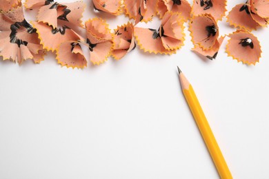 Photo of Sharp graphite pencil and shavings on white background, top view. Space for text