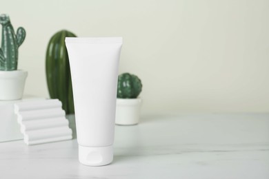 Photo of Tube of hand cream on white marble table, space for text