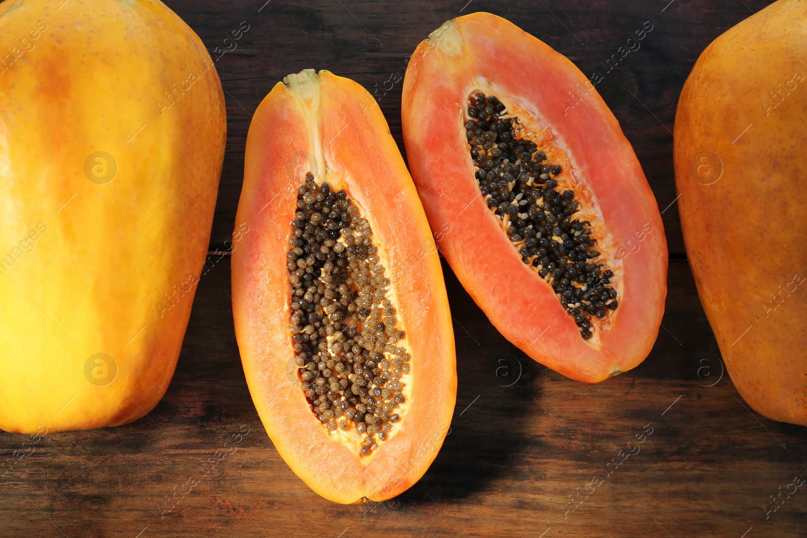 Photo of Fresh ripe cut and whole papaya fruits on wooden table, flat lay