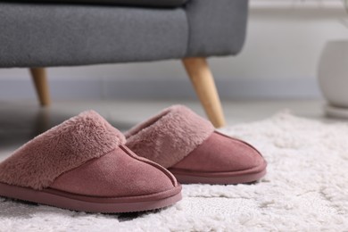 Photo of Pink soft slippers on carpet indoors, closeup. Space for text