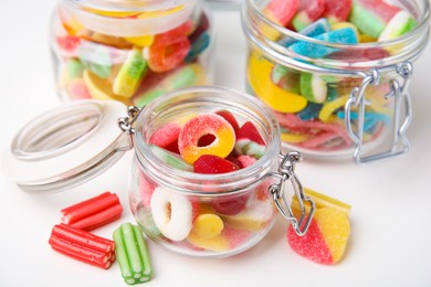 Photo of Tasty jelly candies in jars on white table