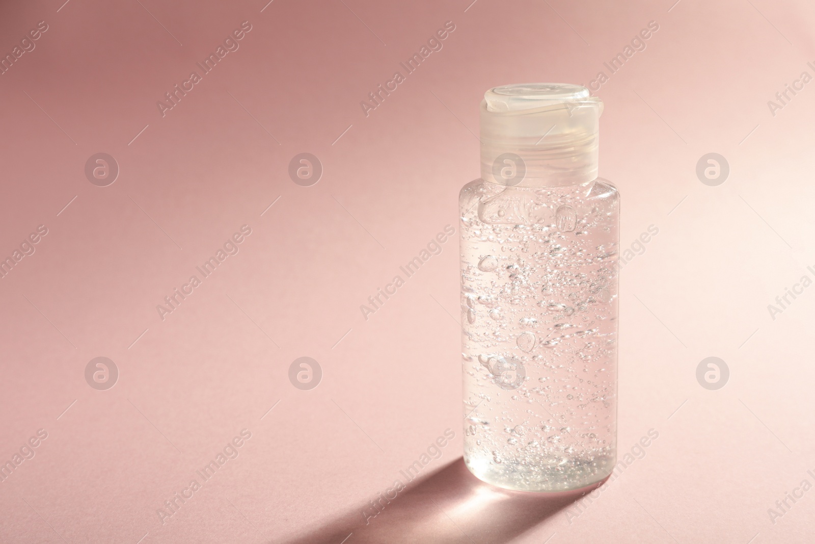 Photo of Bottle of cosmetic gel on pale pink background, space for text