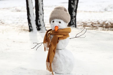 Funny snowman with scarf and hat in winter forest