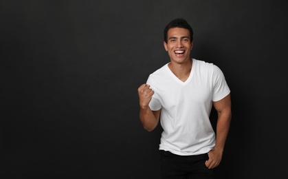 Happy handsome young African-American man on black background