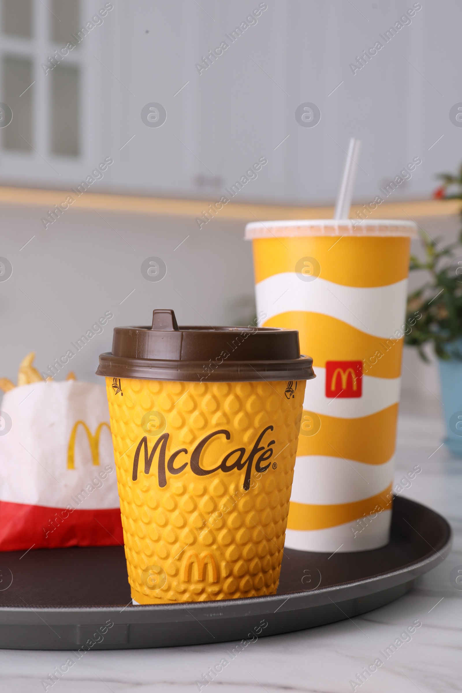 Photo of MYKOLAIV, UKRAINE - AUGUST 12, 2021: Cold and hot McDonald's drinks, French fries on marble table in kitchen