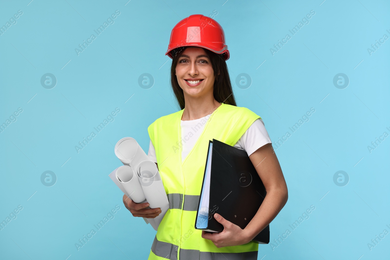Photo of Architect in hard hat with drafts and folder on light blue background