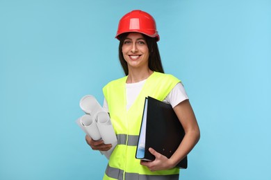 Photo of Architect in hard hat with drafts and folder on light blue background