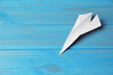 Photo of Handmade paper plane on light blue wooden table. Space for text