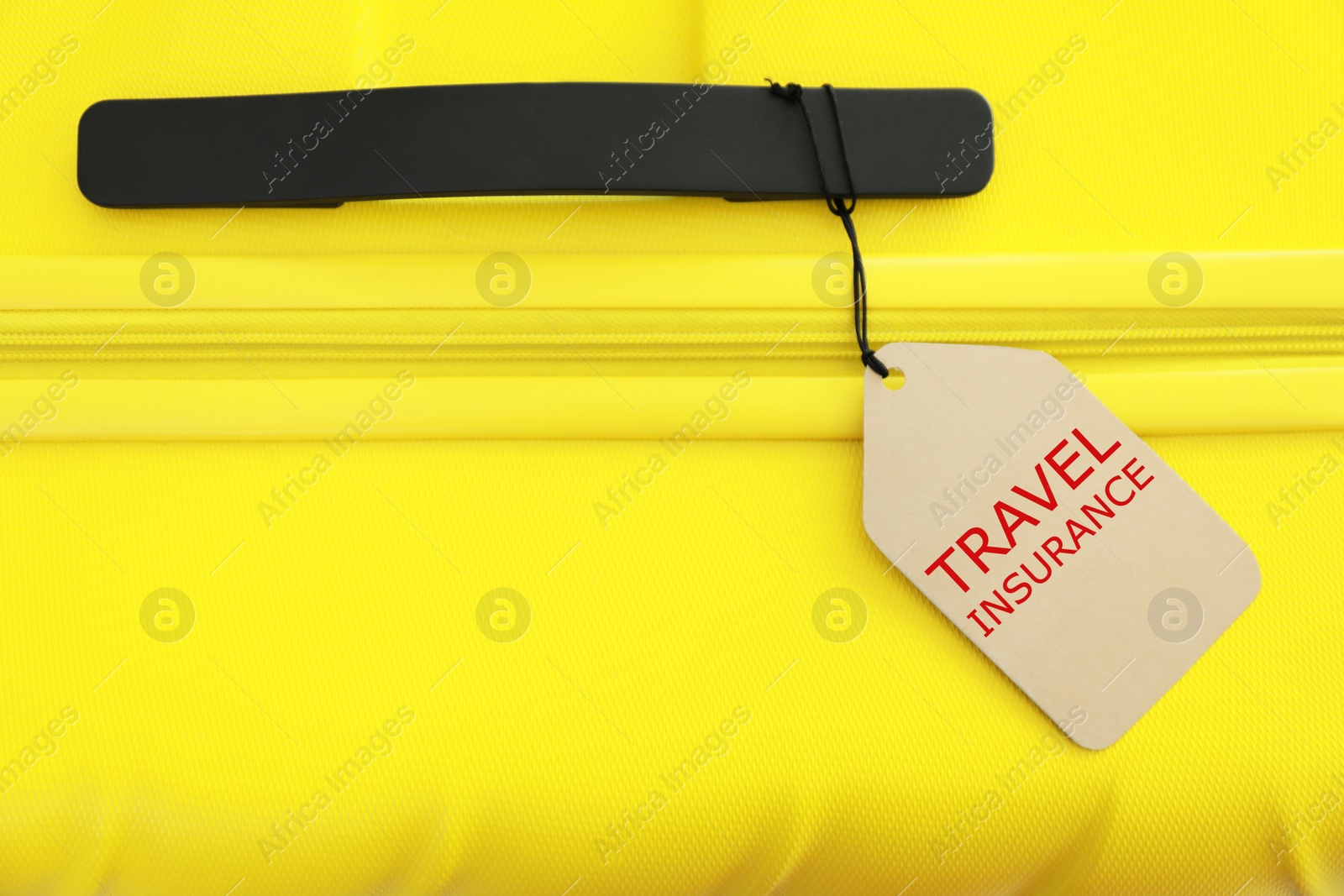 Photo of Yellow suitcase with TRAVEL INSURANCE label, top view