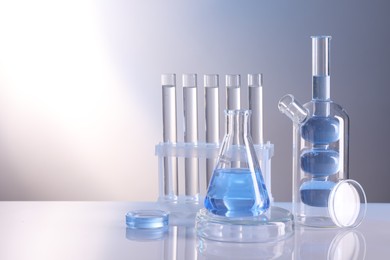 Laboratory analysis. Different glassware on table against light background, space for text