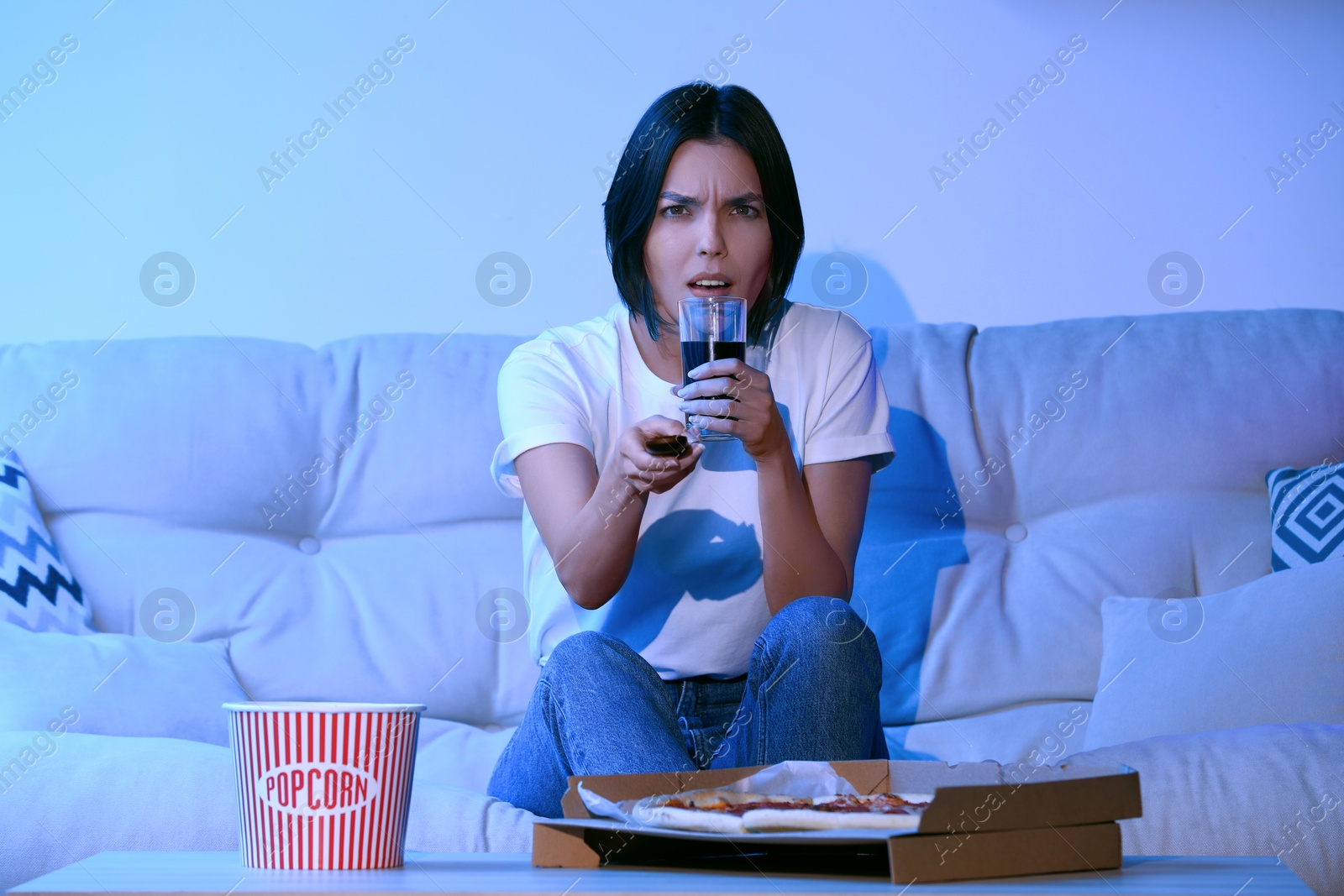 Photo of Emotional woman watching TV with popcorn and pizza on sofa