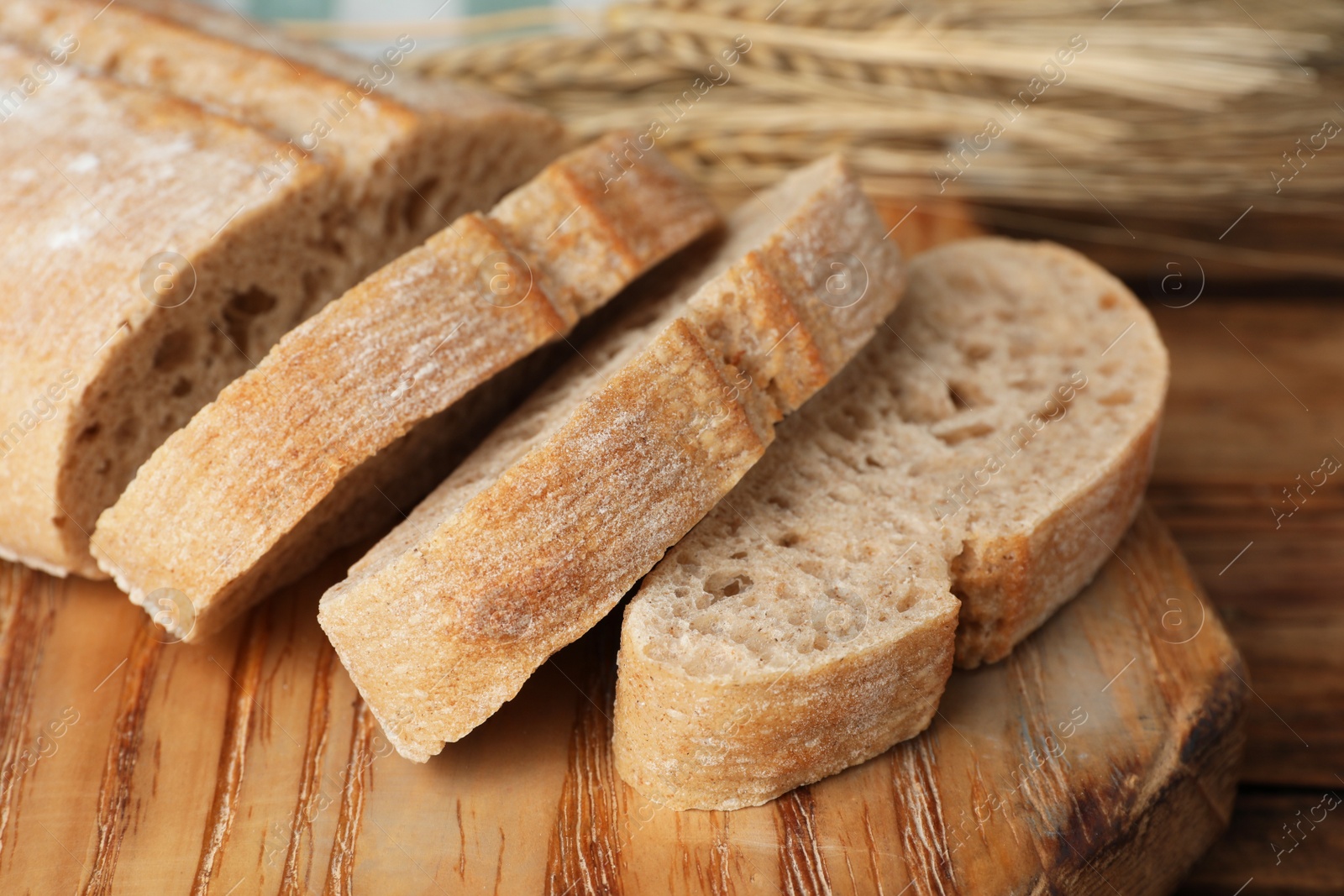 Photo of Cut fresh ciabatta on wooden table, closeup