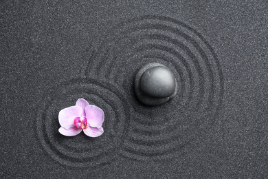 Photo of Stones and orchid flower on black sand with beautiful pattern, flat lay. Zen concept