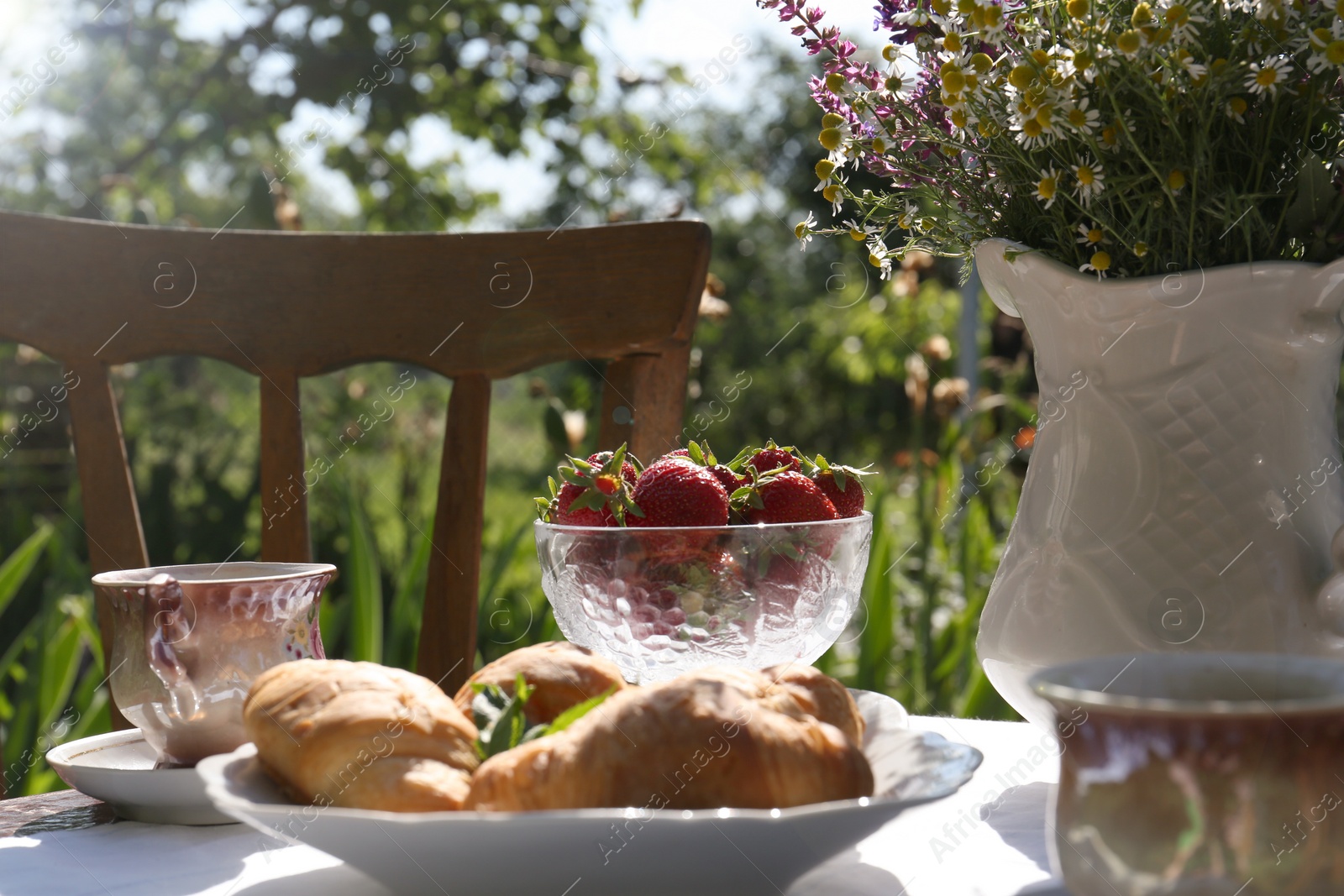 Photo of Beautiful bouquet of wildflowers on table served for tea drinking in garden, closeup