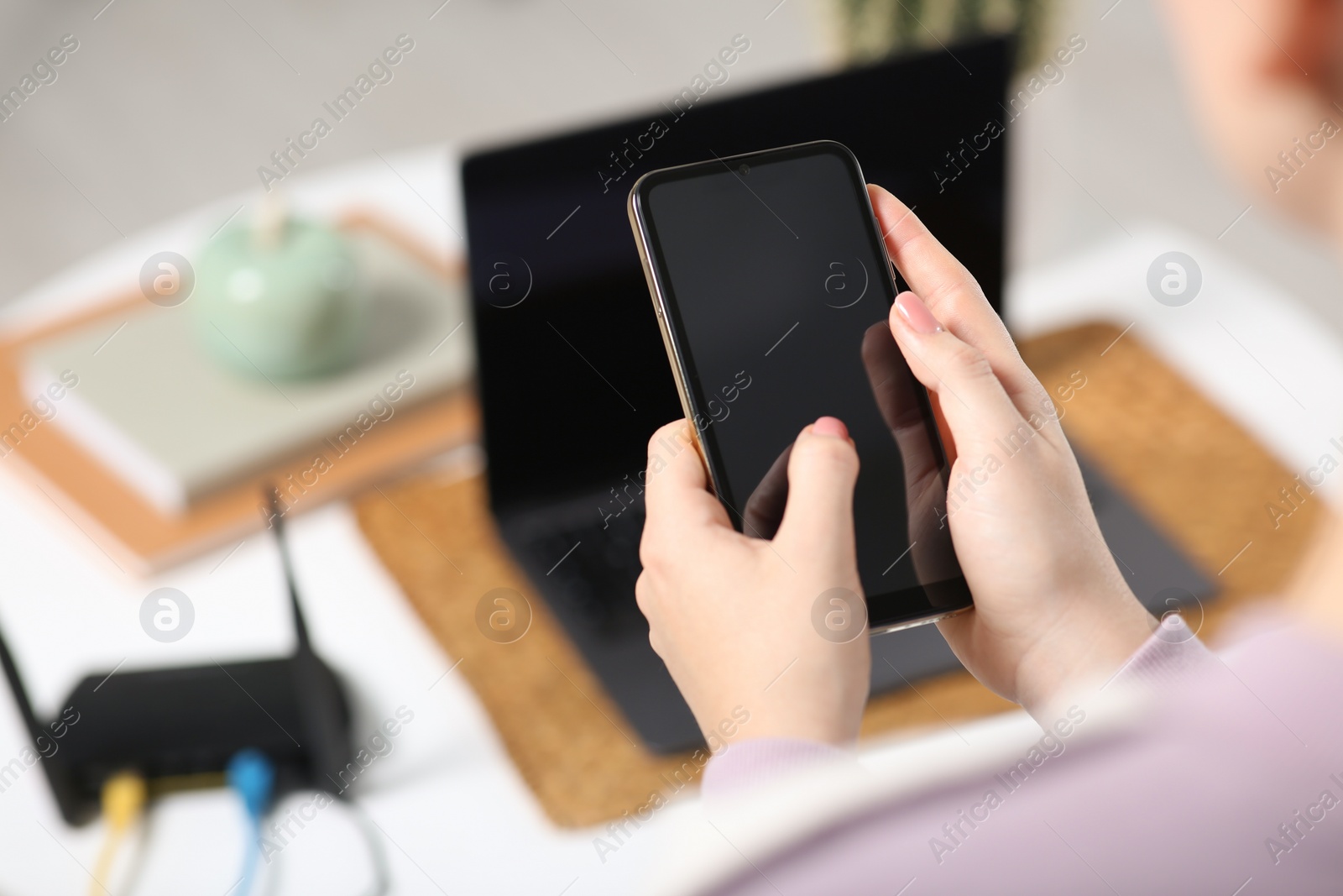 Photo of Woman with smartphone connecting to internet via Wi-Fi router indoors, closeup