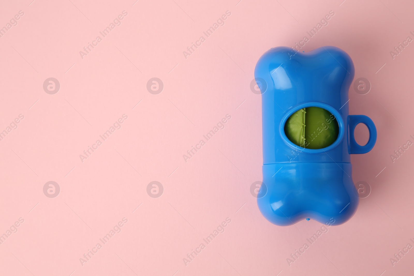 Photo of Dispenser with dog waste bags on pink background, top view. Space for text