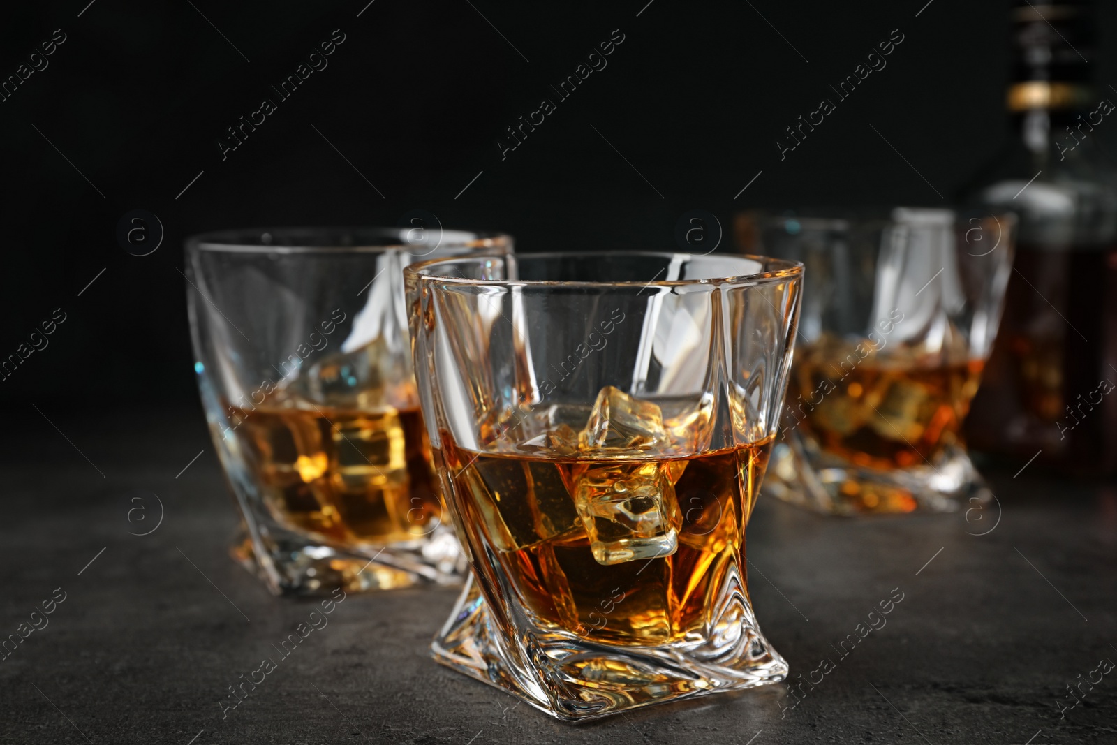 Photo of Golden whiskey in glasses with ice cubes on table