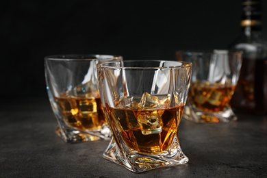 Photo of Golden whiskey in glasses with ice cubes on table