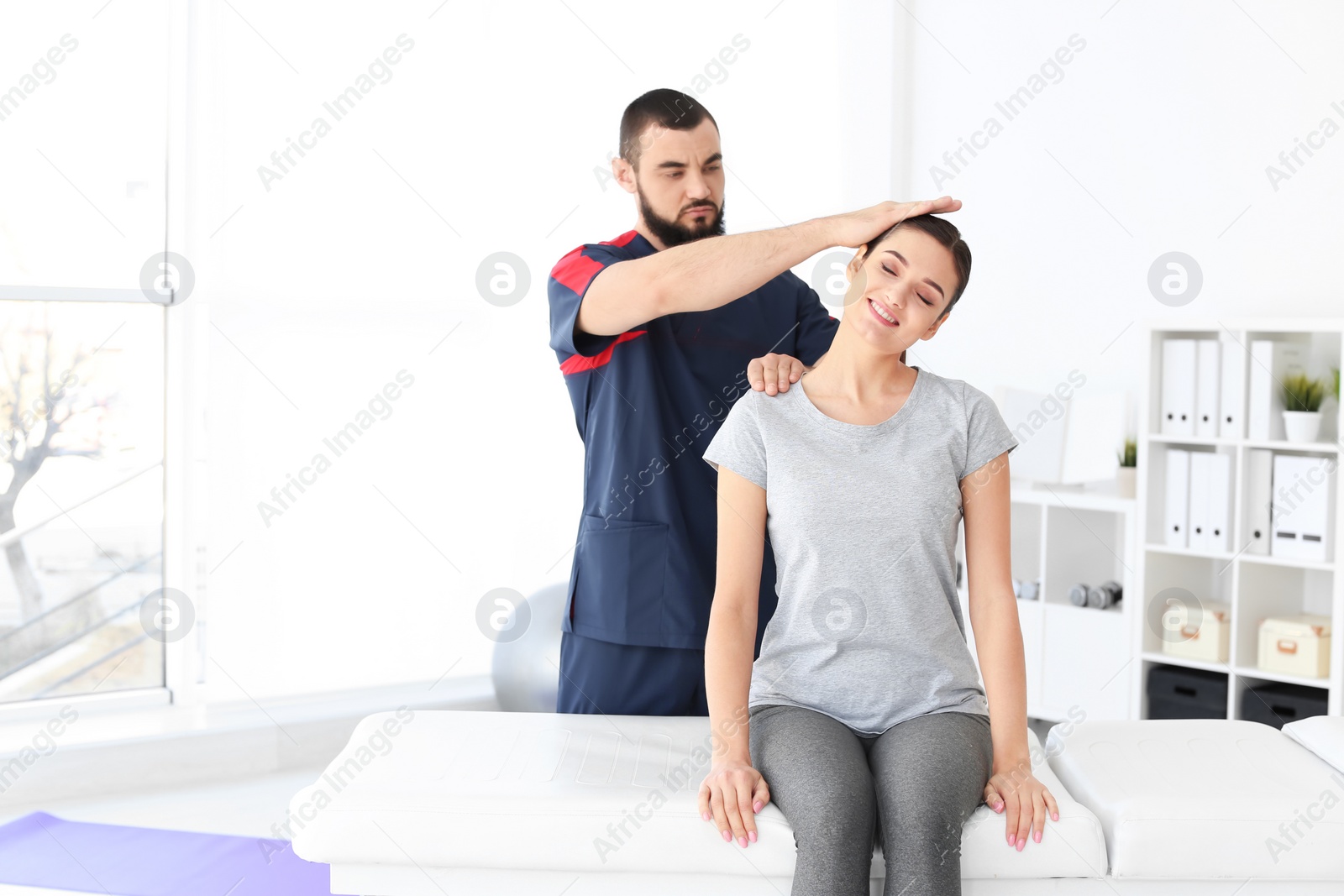 Photo of Physiotherapist working with young female patient in clinic