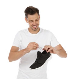 Photo of Man putting capsule shoe freshener in footwear on white background