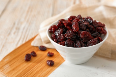 Photo of Dried cranberries in bowl on light table, closeup