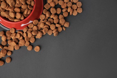 Photo of Dry dog food and feeding bowl on black background, flat lay. Space for text