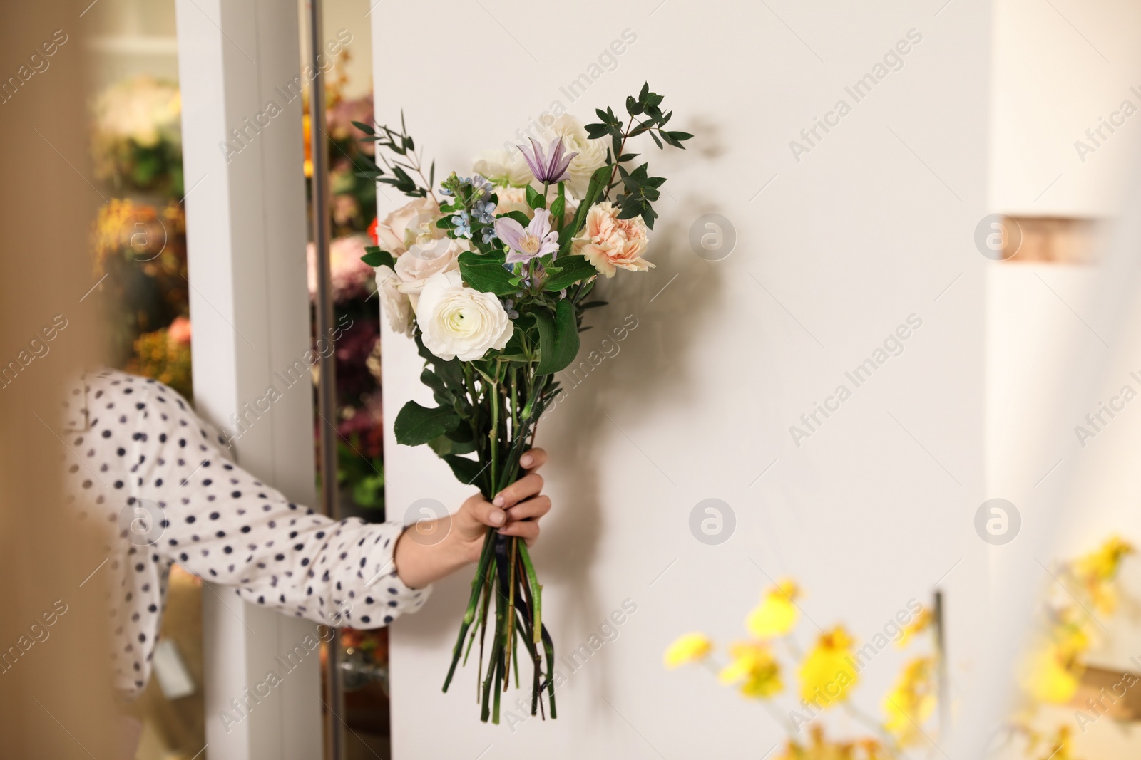 Photo of Professional florist with bouquet of fresh flowers in shop, closeup