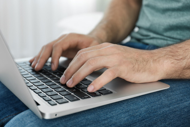 Photo of Man working on modern laptop at home, closeup