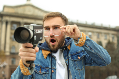 Photo of Young man with vintage video camera on city street