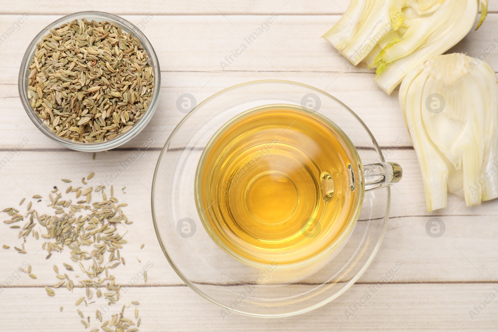 Photo of Aromatic fennel tea, seeds and fresh vegetable on wooden table, flat lay