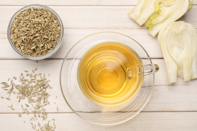 Photo of Aromatic fennel tea, seeds and fresh vegetable on wooden table, flat lay