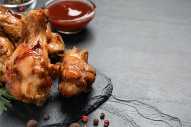 Photo of Delicious fried chicken wings on black table, closeup. Space for text