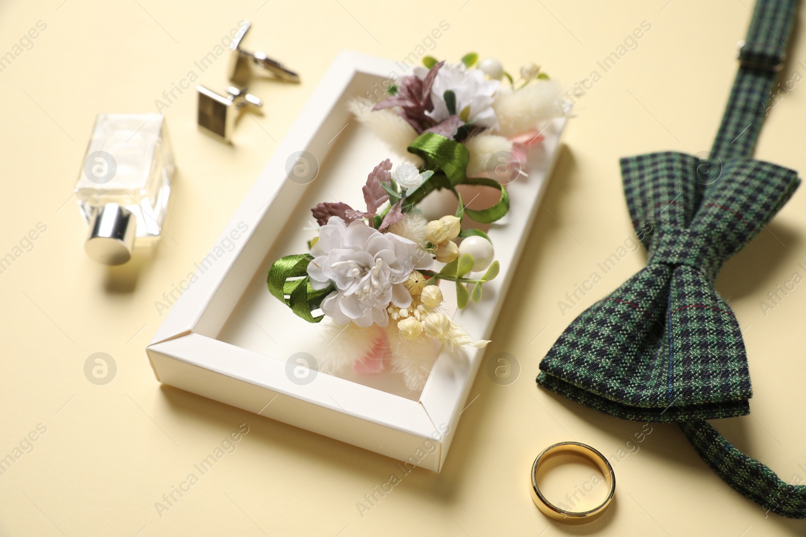 Photo of Wedding stuff. Composition with stylish boutonniere on yellow background, closeup