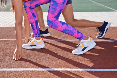 Sporty couple ready for running at stadium on sunny morning