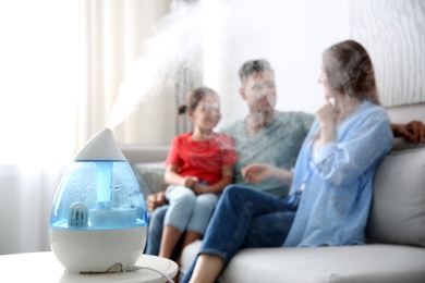 Modern air humidifier and blurred family on background