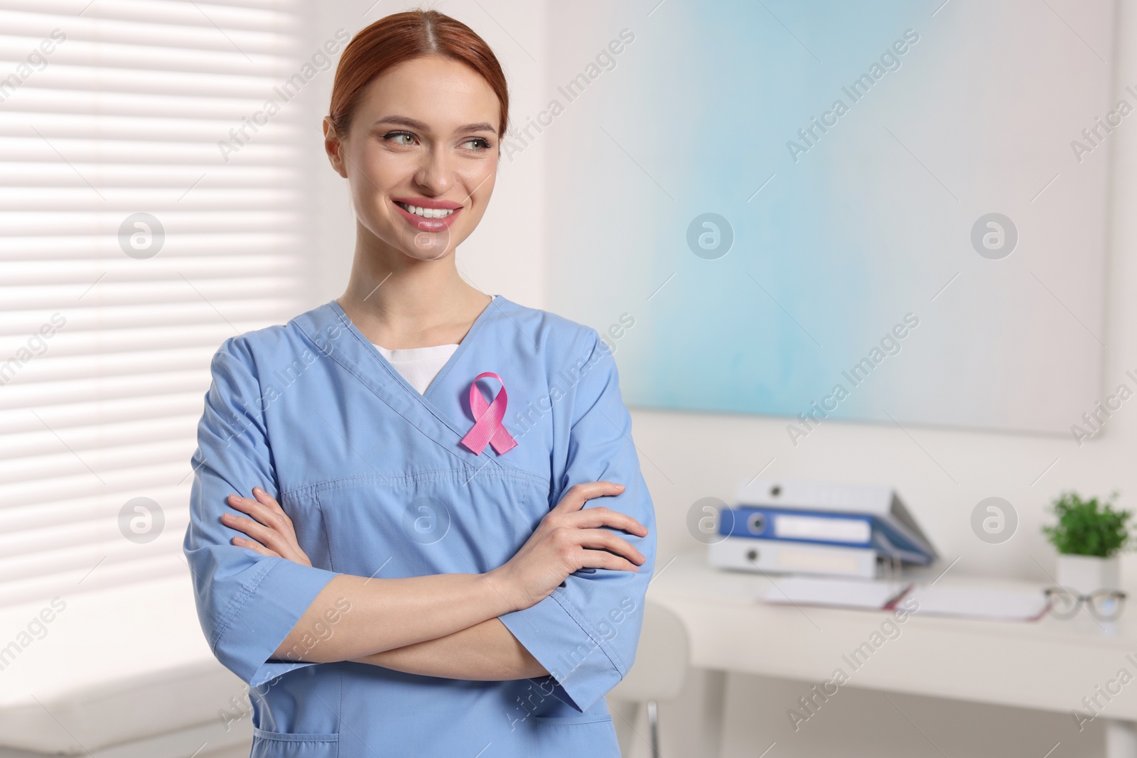 Photo of Mammologist with pink ribbon in hospital, space for text. Breast cancer awareness