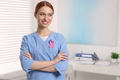 Photo of Mammologist with pink ribbon in hospital, space for text. Breast cancer awareness