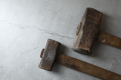 Two sledgehammers on grey textured background, top view. Space for text