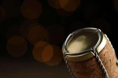 Photo of Closeup view of sparkling wine cork and muselet cap against blurred festive lights, space for text. Bokeh effect