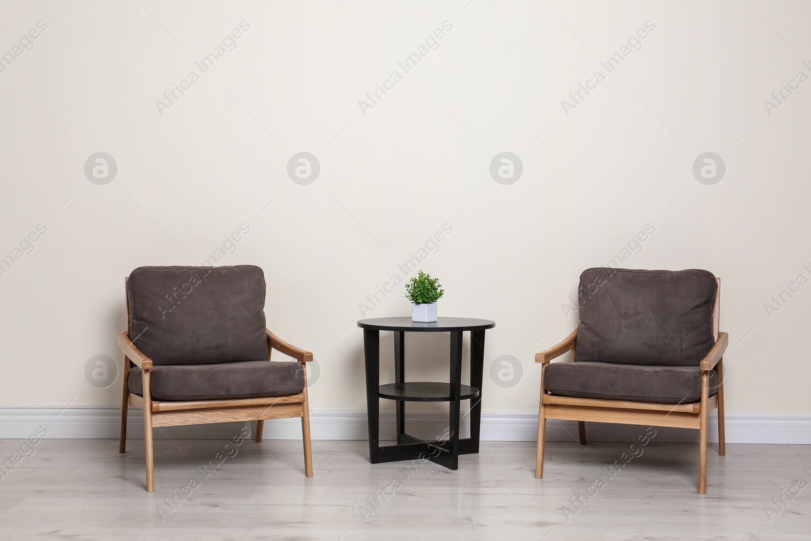 Photo of Room interior with modern armchairs and table near light wall