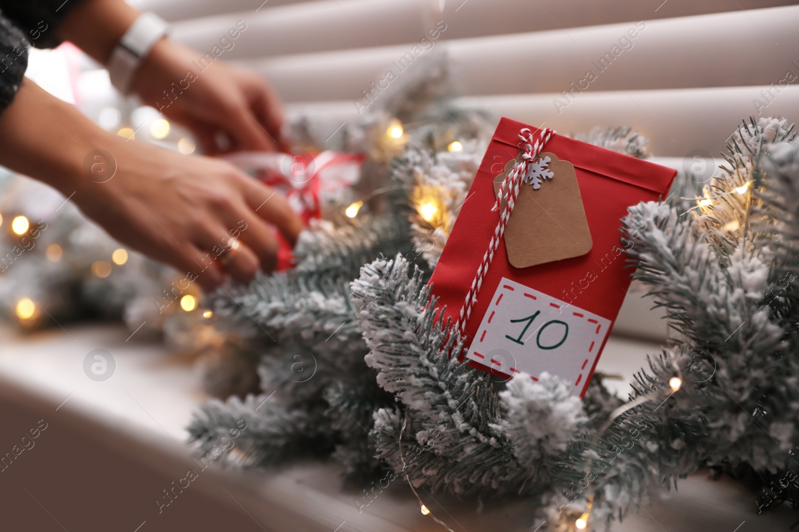 Photo of Woman making Christmas advent calendar, focus on paper bag with gift