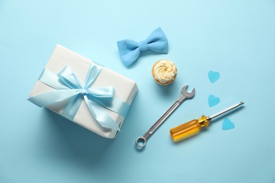 Gift box, cupcake and men accessories on light blue background, flat lay. Father's day celebration