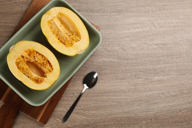 Halves of fresh spaghetti squash in baking dish on wooden table, flat lay with space for text. Cooking at home