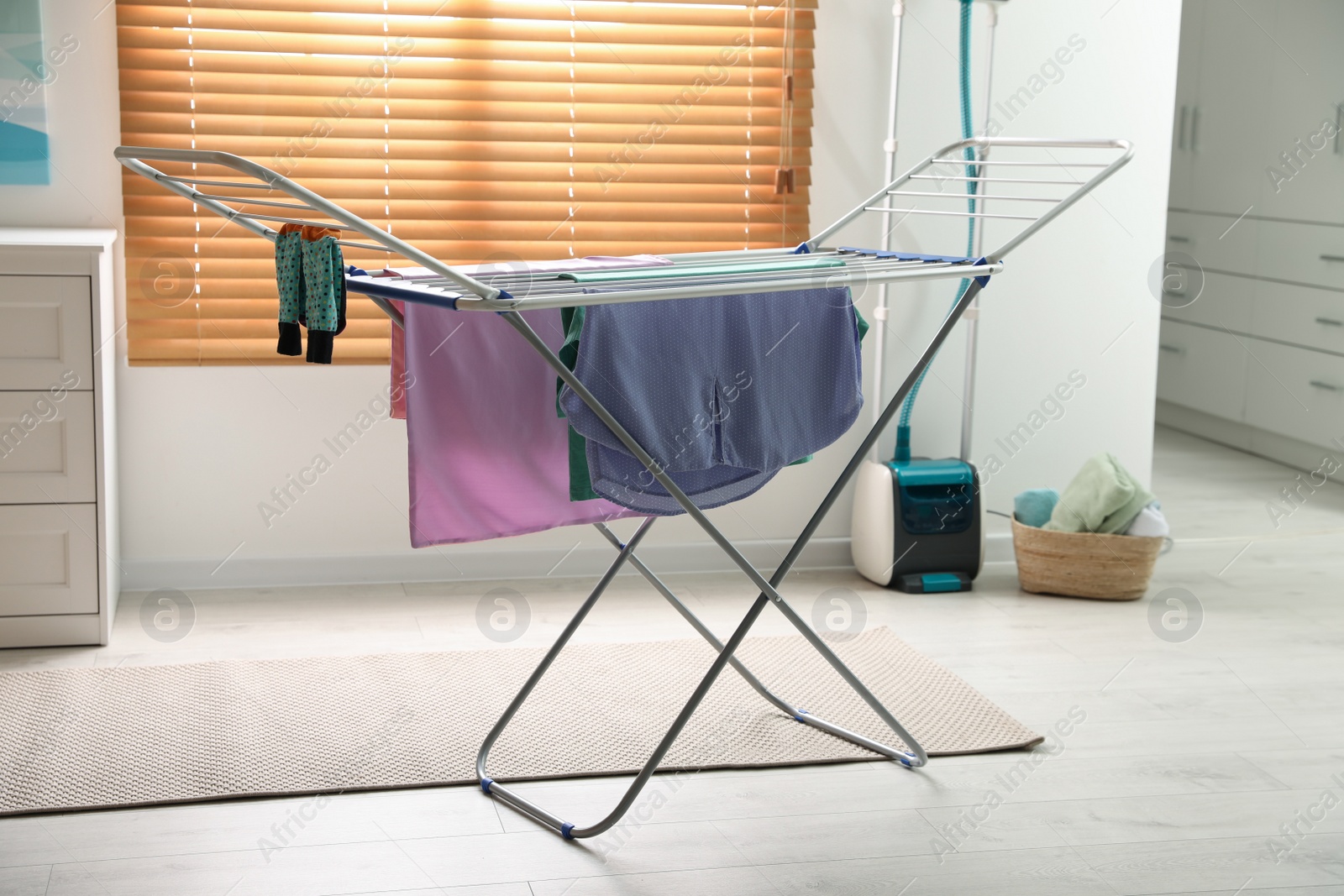 Photo of Clean laundry hanging on drying rack indoors
