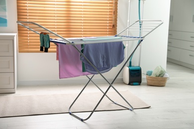 Clean laundry hanging on drying rack indoors