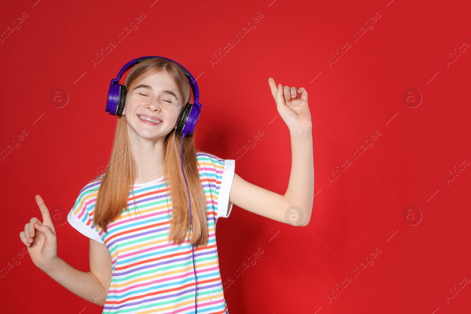 Photo of Teenage girl enjoying music in headphones on color background. Space for text